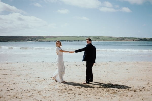 Bride and groom holding hands on beach