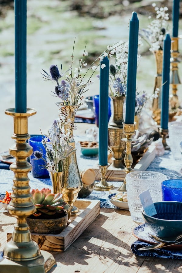 Gold candlesticks with blue candles down middle of wedding table