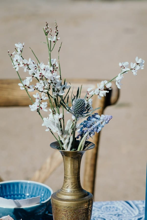 White flowers and thistle in gold vase