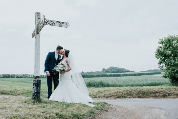Bride and groom kissing by sign post