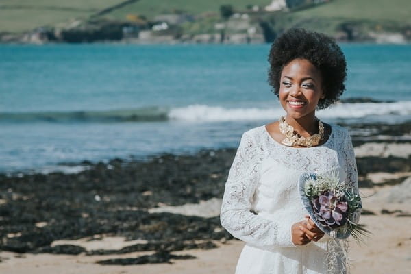 Bride holding bouquet as she walks on beach