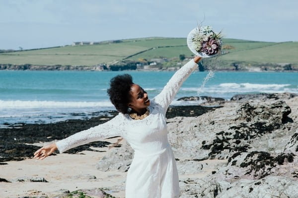 Bride holding out arms on beach