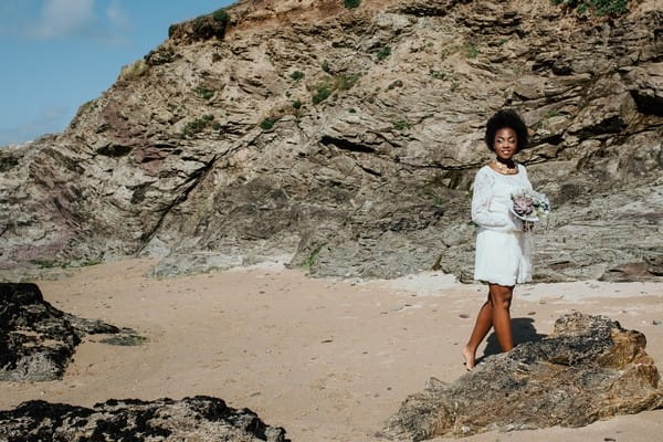 Bride walking by rocks on beach