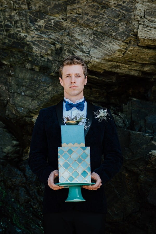 Groom holding light blue wedding cake