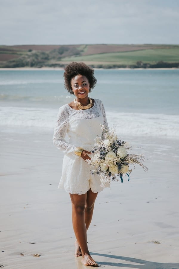 Bride standing on beach holding bouquet