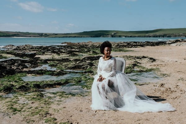 Bride sitting on chair on beach