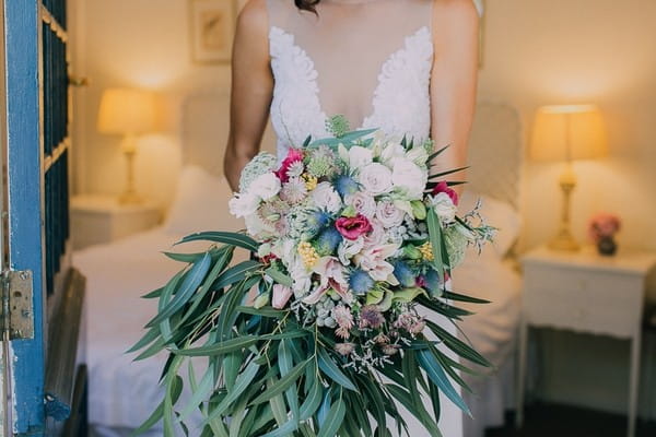 Bride holding large bouquet of flowers and foliage