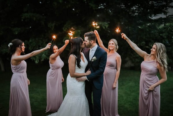 Bridesmaids holding sparklers around bride and groom