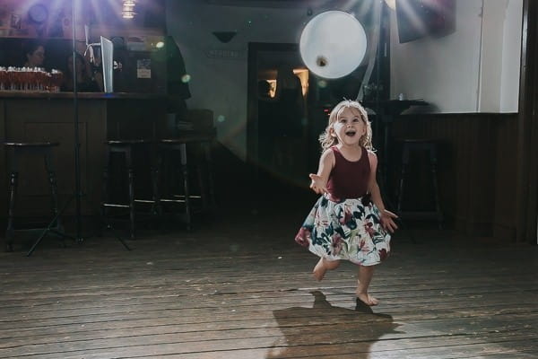 Young girl playing with balloon on dance floor at wedding