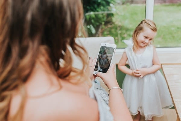 Bridesmaid taking picture of flower girl