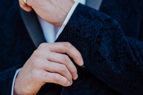 Groom touching suit jacket cuff