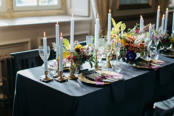 Flowers and candles on wedding table with dark tablecloth