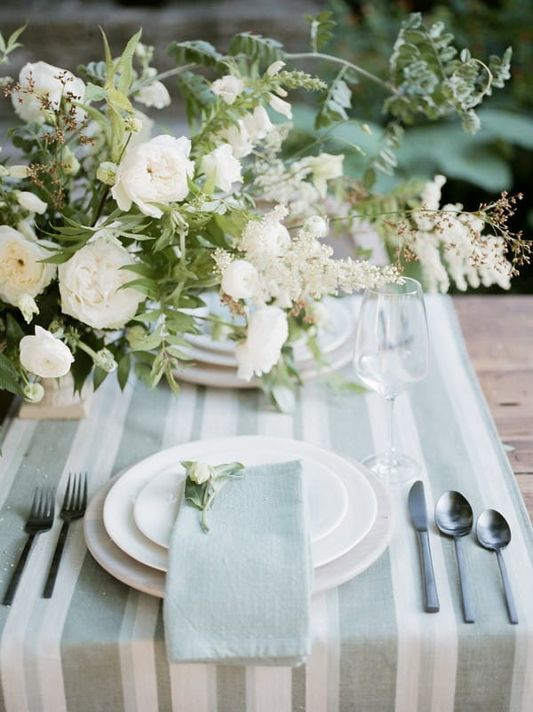 Simple and elegant wedding place setting with flowers and striped runner