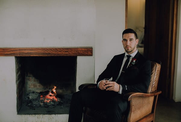Groom sitting in chair by fire