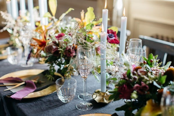 Flowers, candles and glassware on dark tablecloth