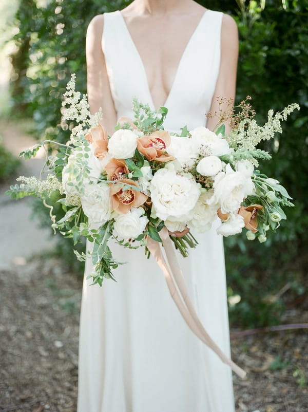 Bride holding peach and white bridal bouquet