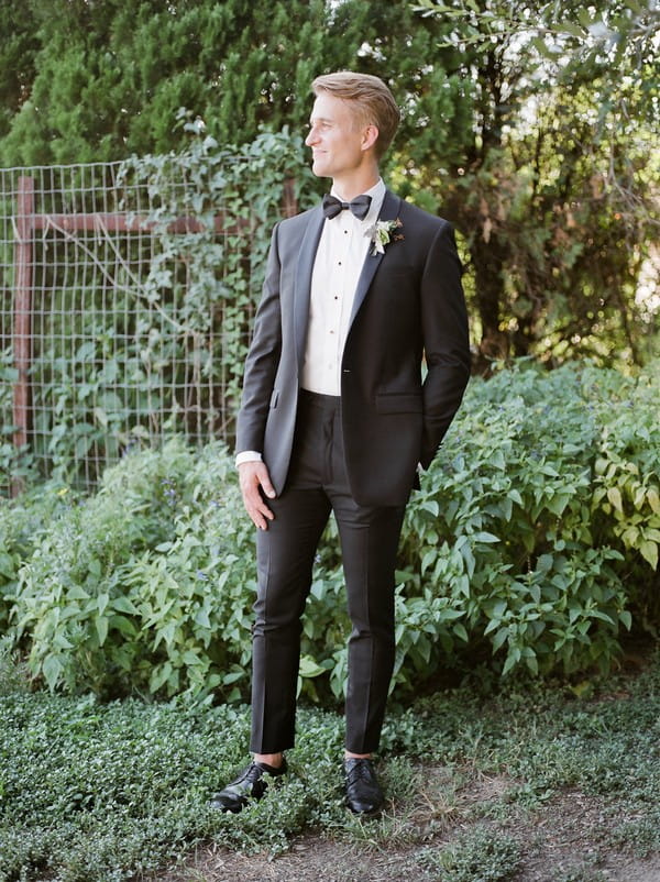 Groom wearing black suit with bow tie