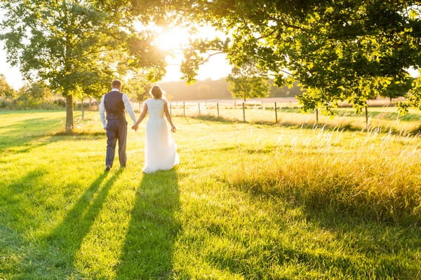 Bride and groom by trees in sunshine - Picture by Heather Jackson Photography