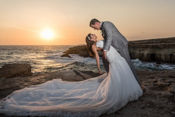 Groom leaning bride back by sea at sunset - Picture by Lee Stuart Photography