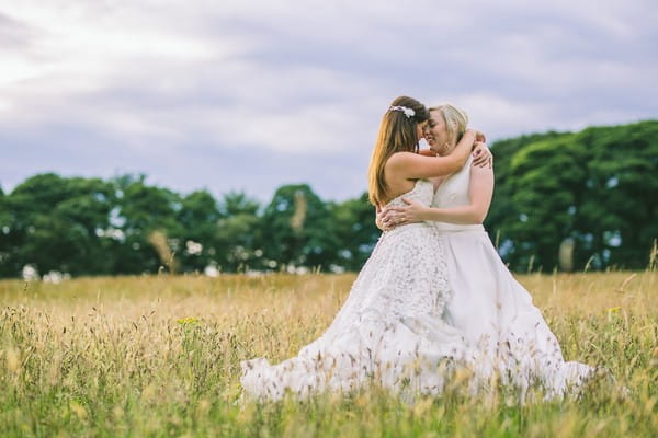 Two brides hugging in a field - Picture by Nik Bryant Photography