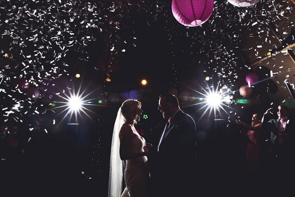 Excited bride and groom facing each other on dance floor with mouths wide open - Picture by Katie Sidell Photography