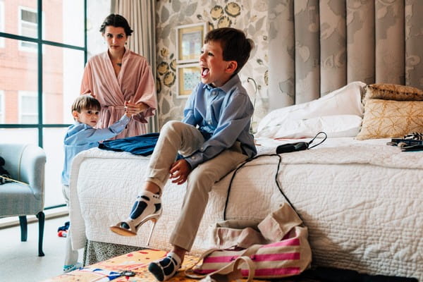 Youg boy sitting on bed putting on bridal shoe - Picture by Damion Mower Photography