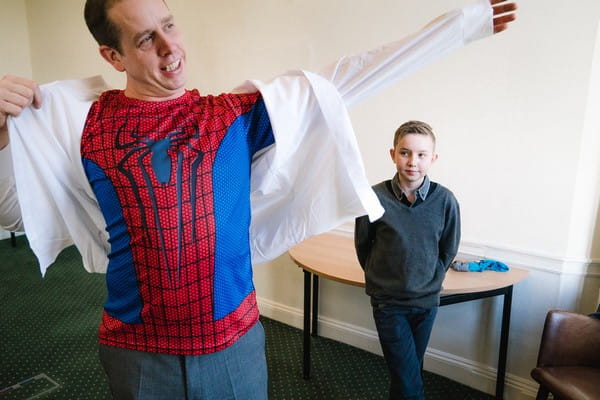 Boy looking embarrassed as man puts shirt on over top of Spiderman top - Picture by Married to my Camera