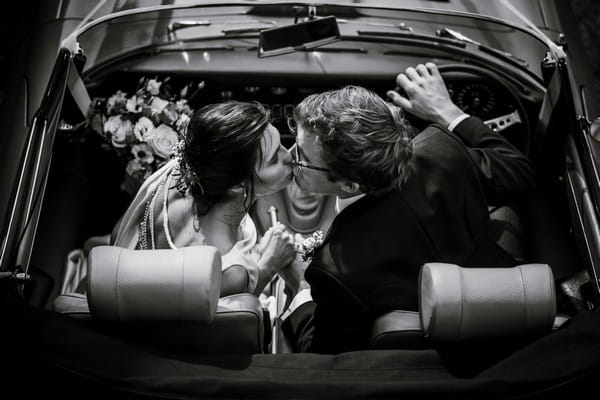 Bride and groom kissing in front seats of wedding car - Picture by Lee Dann Photography