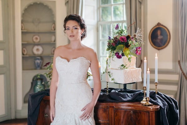 Bride standing next to wedding cake