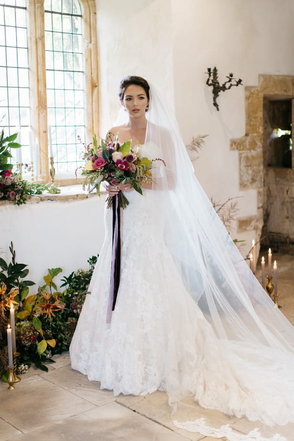 Bride with long veil holding bouquet