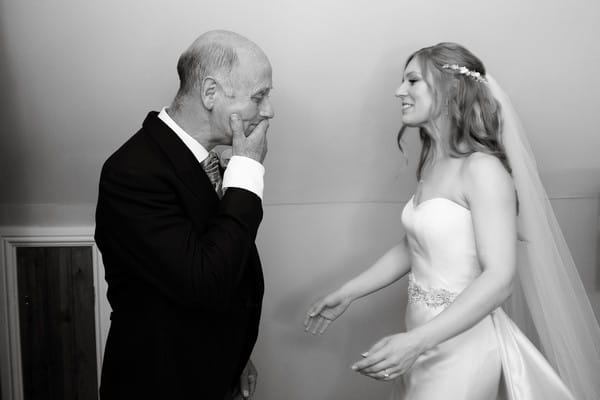 Father with hand over his mouth when he sees his daughter in wedding dress