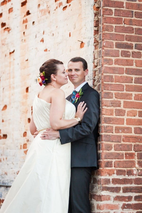 Bride and groom leaning against a wall