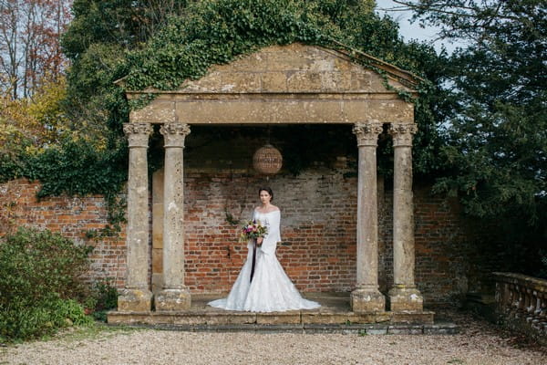 Bride under stone structure in grounds of Brympton House