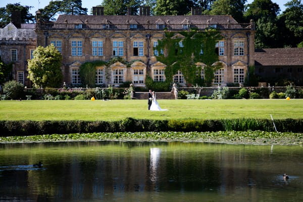 Bride and groom by pond at Brympton House