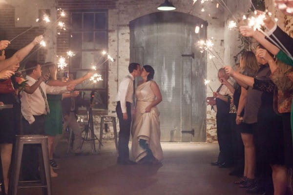 Bride and groom kissing in the middle of guests holding sparklers