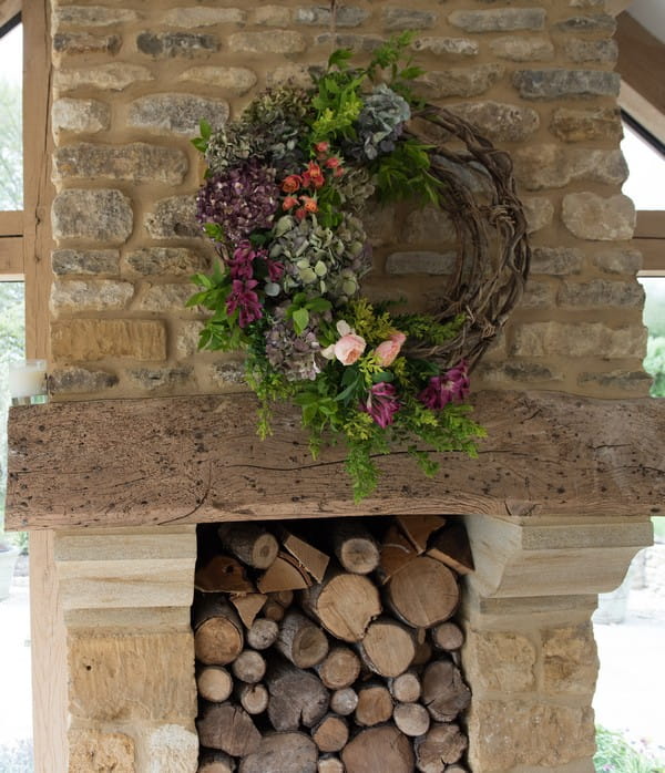 Wreath hanging over log-filled fireplace