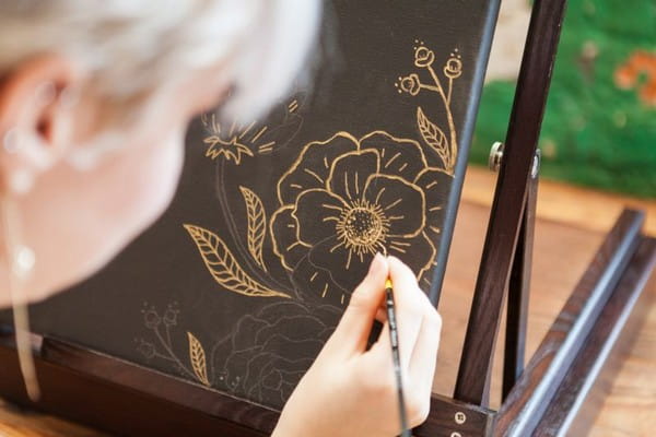 Woman drawing gold flowers on wedding guest book