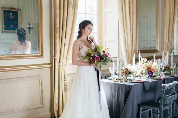 Bride holding bridal bouquet next to wedding table
