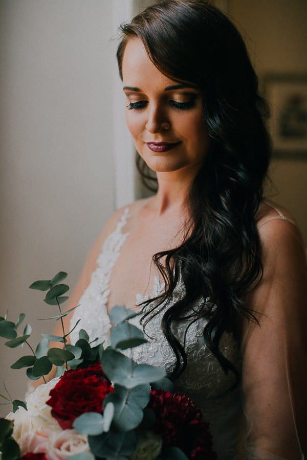 Bride with hair down hairstyle looking down at bouquet