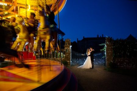 Bride and groom next to funfair carousel at Brympton House Wedding