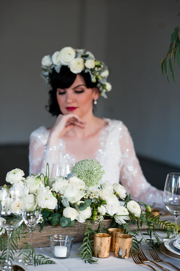 Bride with flower crown looking down at wedding table