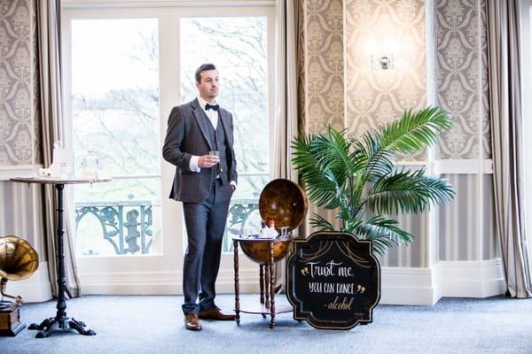 1920s groom standing next to drinks globe
