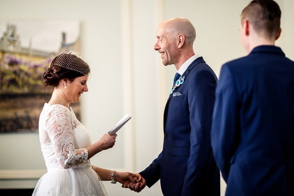 Groom holding bride's hand as she reads vows