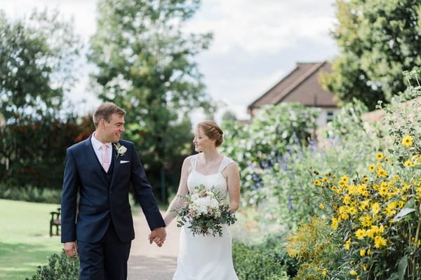 Bride and groom walking in gardens of Langtons House