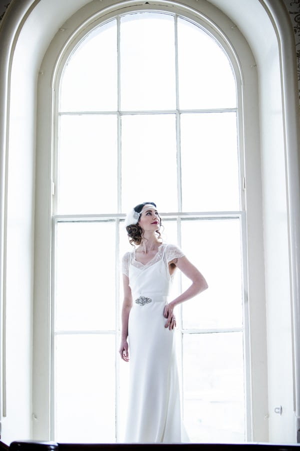 1920s bride standing in front of large window at The Duke of Cornwall Hotel