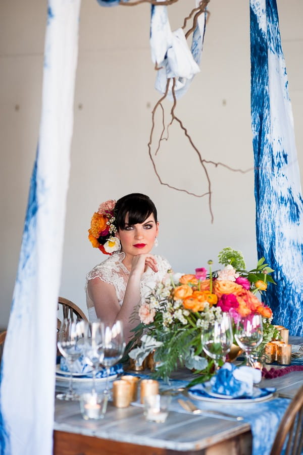 Bride sitting at wedding table with colourful flowers