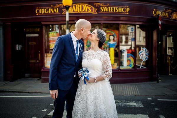 Bride and groom kissing outside sweet shop