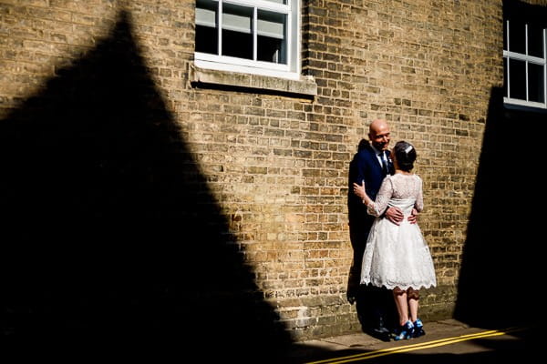 Bride and groom leaning against wall