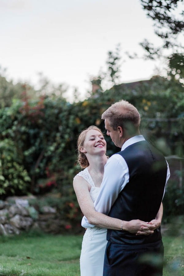 Bride and groom with arms around each other in their garden