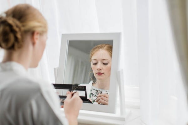 Bride doing make-up in mirror